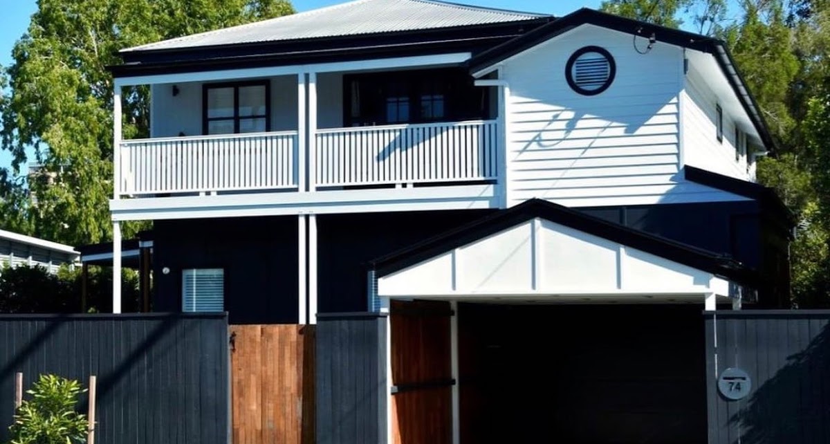 White and blue post war wooden australian house with a fence and a garage