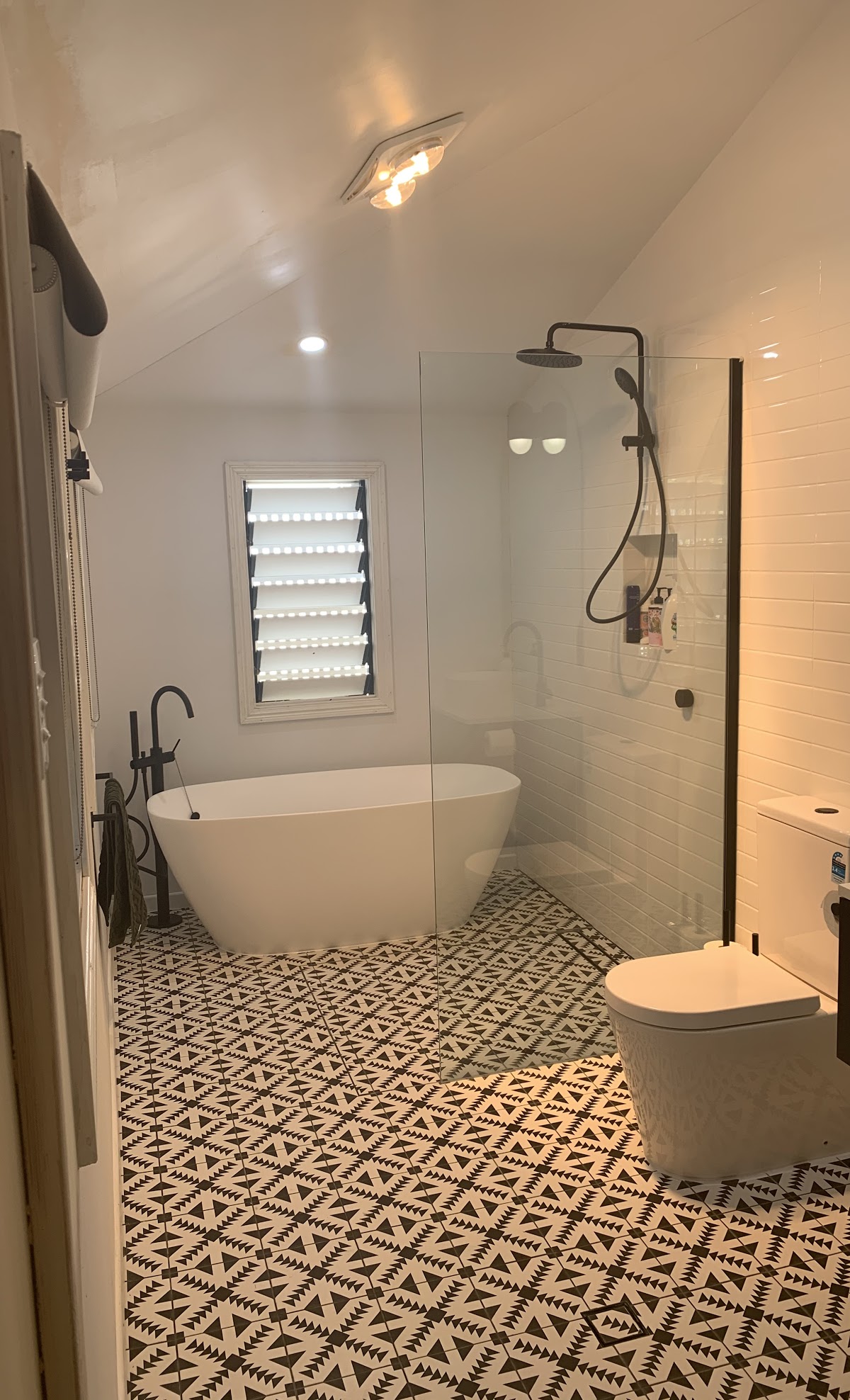 white marble bathroom with a toilet and shower that has mosaic floor tiles