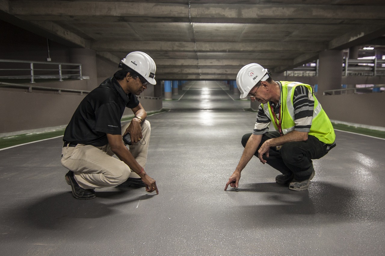 two construction workers crouching and pointing at the floor while doing bedding and levelling