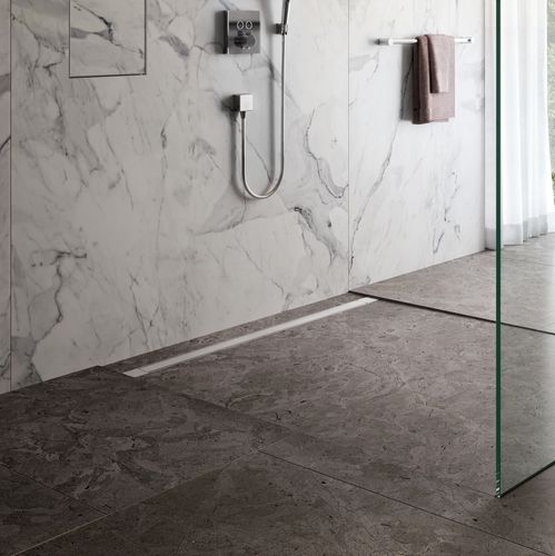 a shower with a lineal drainage system and white marble walls