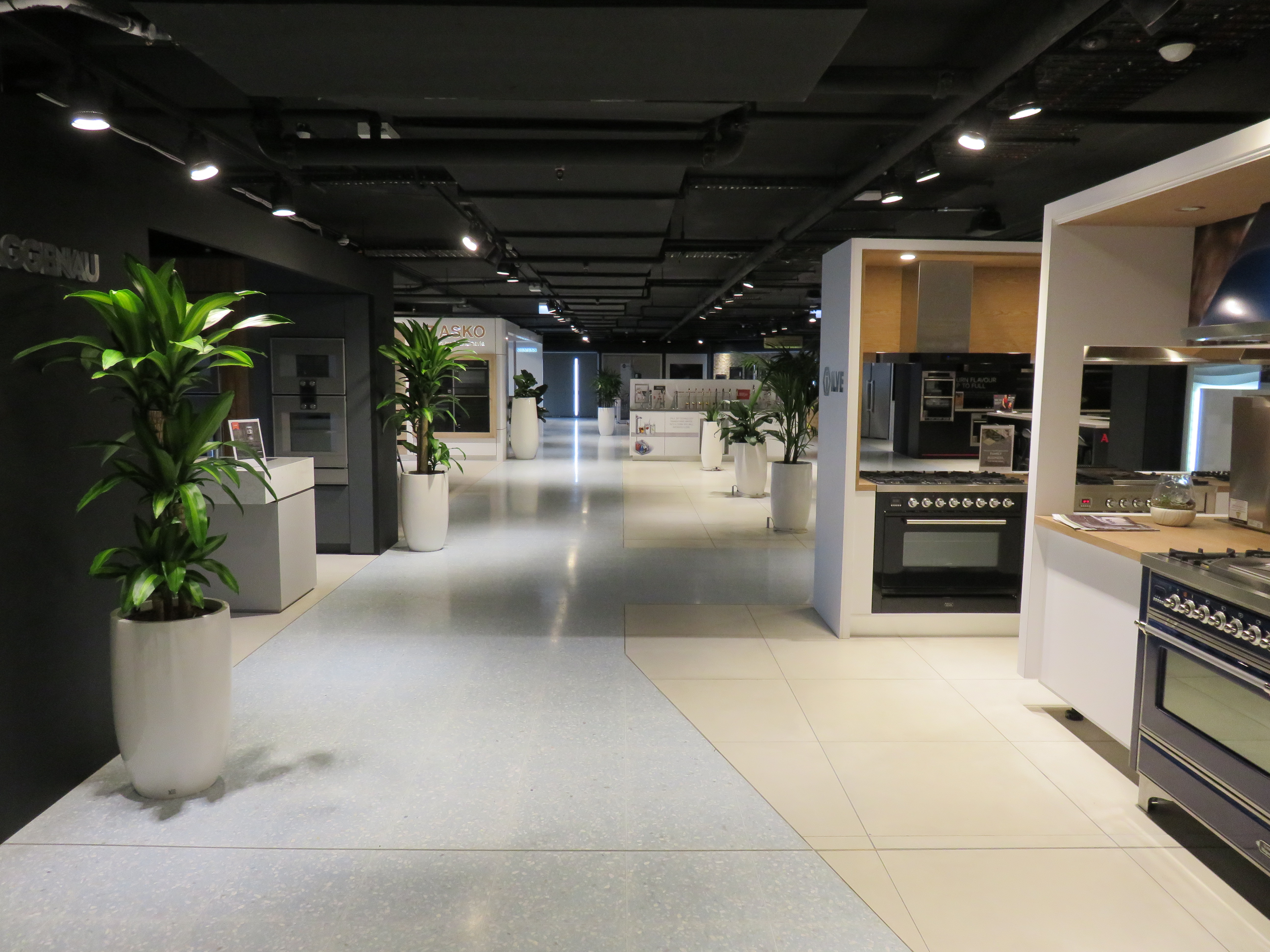 Kitchen showroom with ovens and benchtops on beige and grey tiles